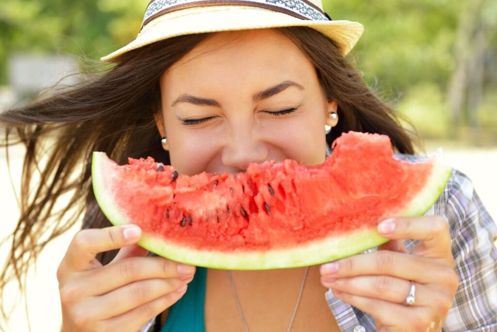 A woman eating a slice of watermelon.